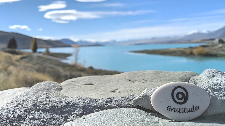 Beautiful New Zealand lake with Gratitude Stone in foreground.
