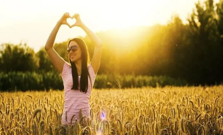 Young lady in a golden field expressing gratitude